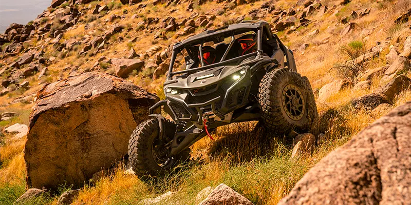 A Can-Am Maverick kicking up dust on a challenging, rocky Texas trail.
